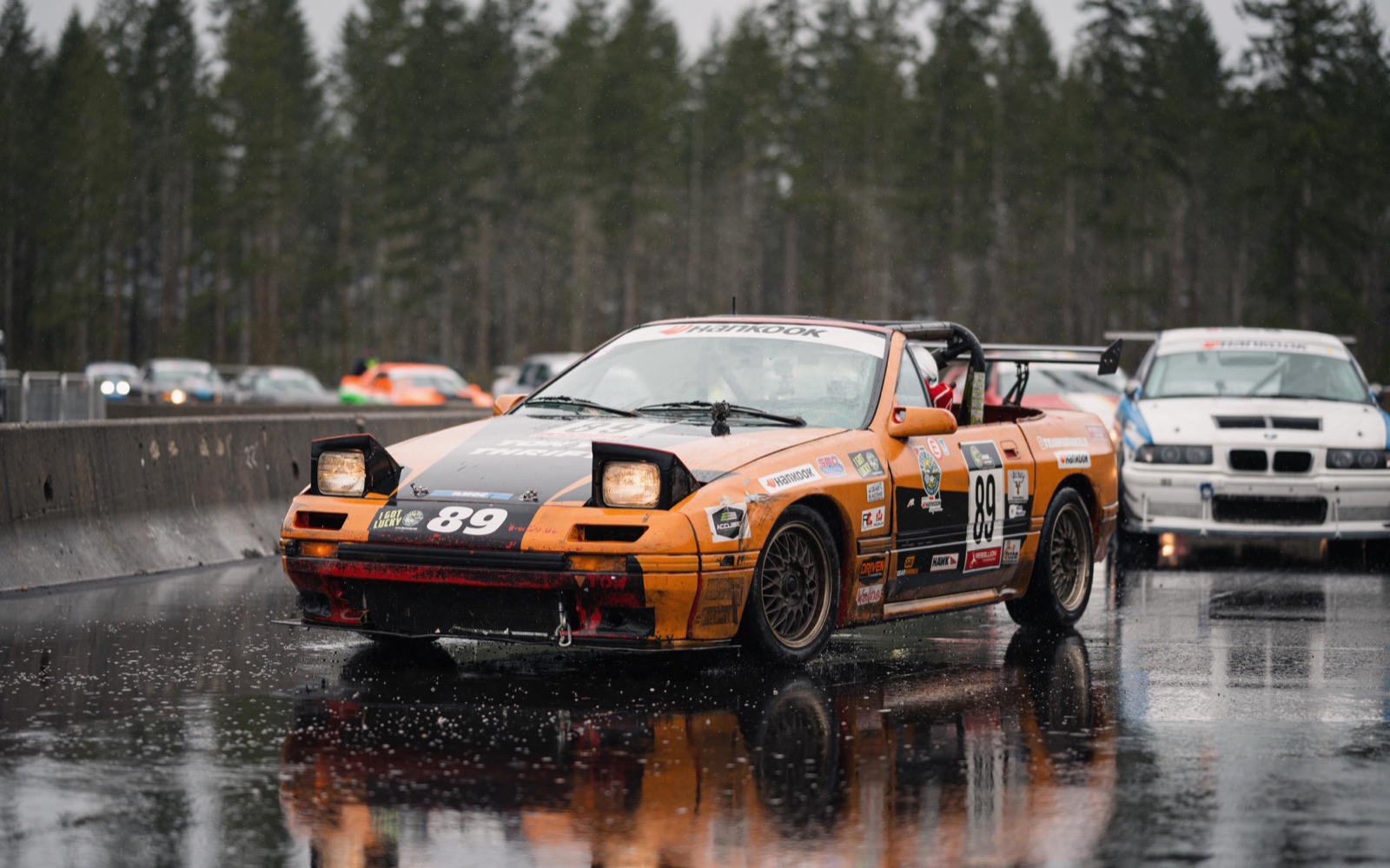 #89 RX-7 with headlights up on a wet track